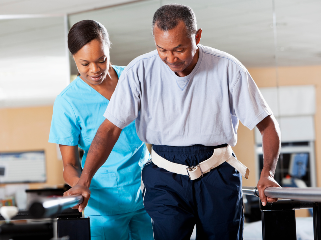 A nurse helping an older man with a gait belt.