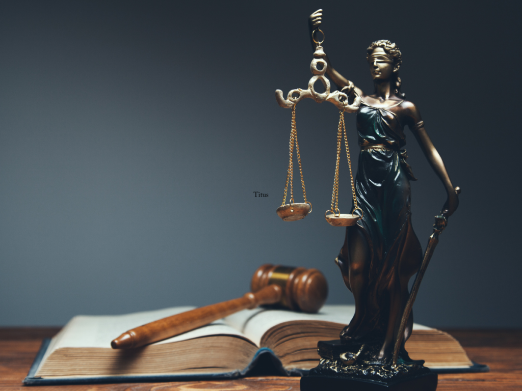 A statue of the lady of justice and a judges gavel on a table.